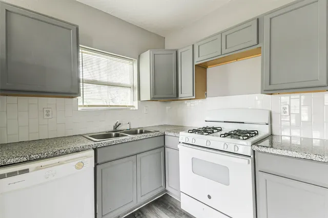 a kitchen with cabinets appliances a sink and a window