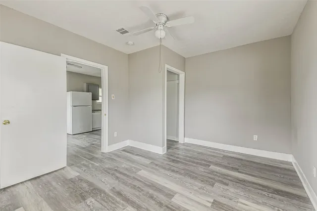 an empty room with wooden floor and ceiling fan