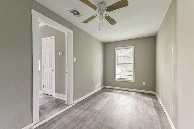 a view of empty room with wooden floor and fan