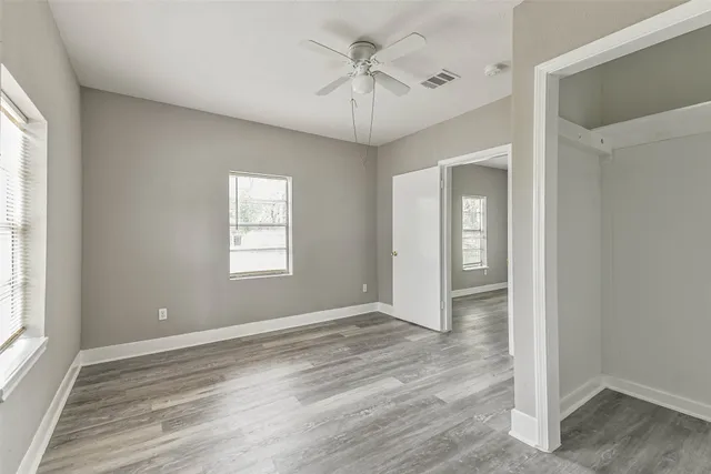a view of an empty room with a window and wooden floor