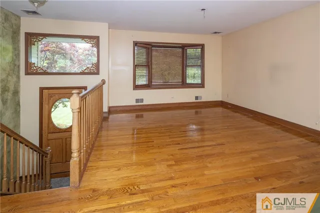 a view of an empty room with window and wooden floor