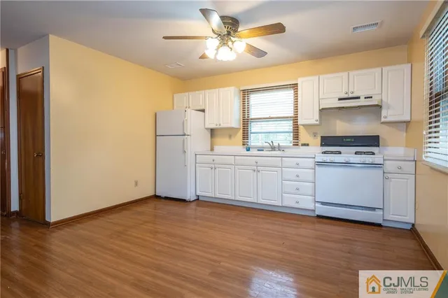 a large kitchen with cabinets wooden floor and a sink
