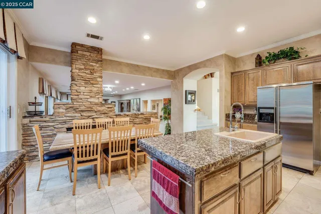 a kitchen with stainless steel appliances granite countertop a stove top oven a sink dishwasher a dining table and chairs with wooden floor