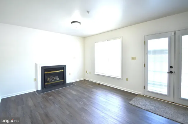 an empty room with wooden floor fireplace and windows
