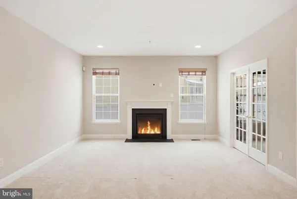 an empty room with windows and chandelier fan