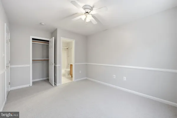 an empty room with chandelier fan and windows