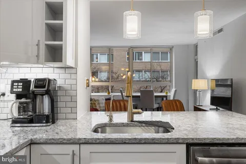 a kitchen with stainless steel appliances a refrigerator a sink dishwasher a dining table and chairs with wooden floor