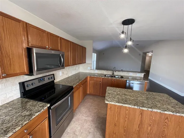 a kitchen with stainless steel appliances granite countertop a sink stove and microwave