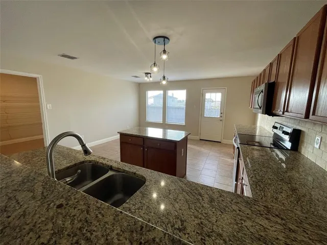 a kitchen with granite countertop a sink and a stove top oven