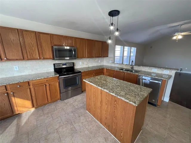 a kitchen with granite countertop a sink counter top space appliances and cabinets