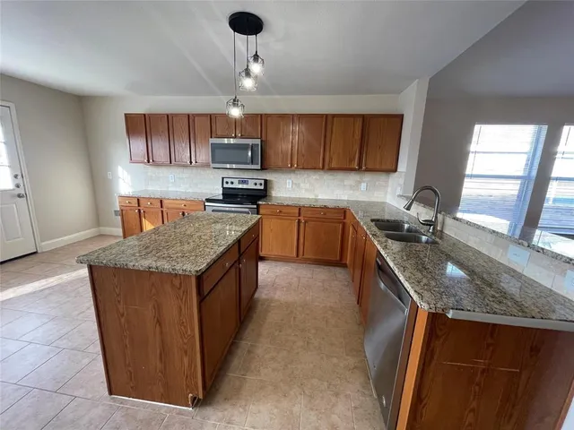 a kitchen with kitchen island granite countertop a sink a counter top space appliances and cabinets