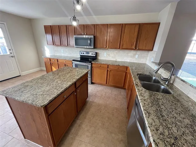 a kitchen with kitchen island granite countertop a sink a counter top space appliances and cabinets