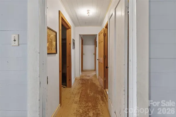 a view of a hallway with wooden floor and a bathroom