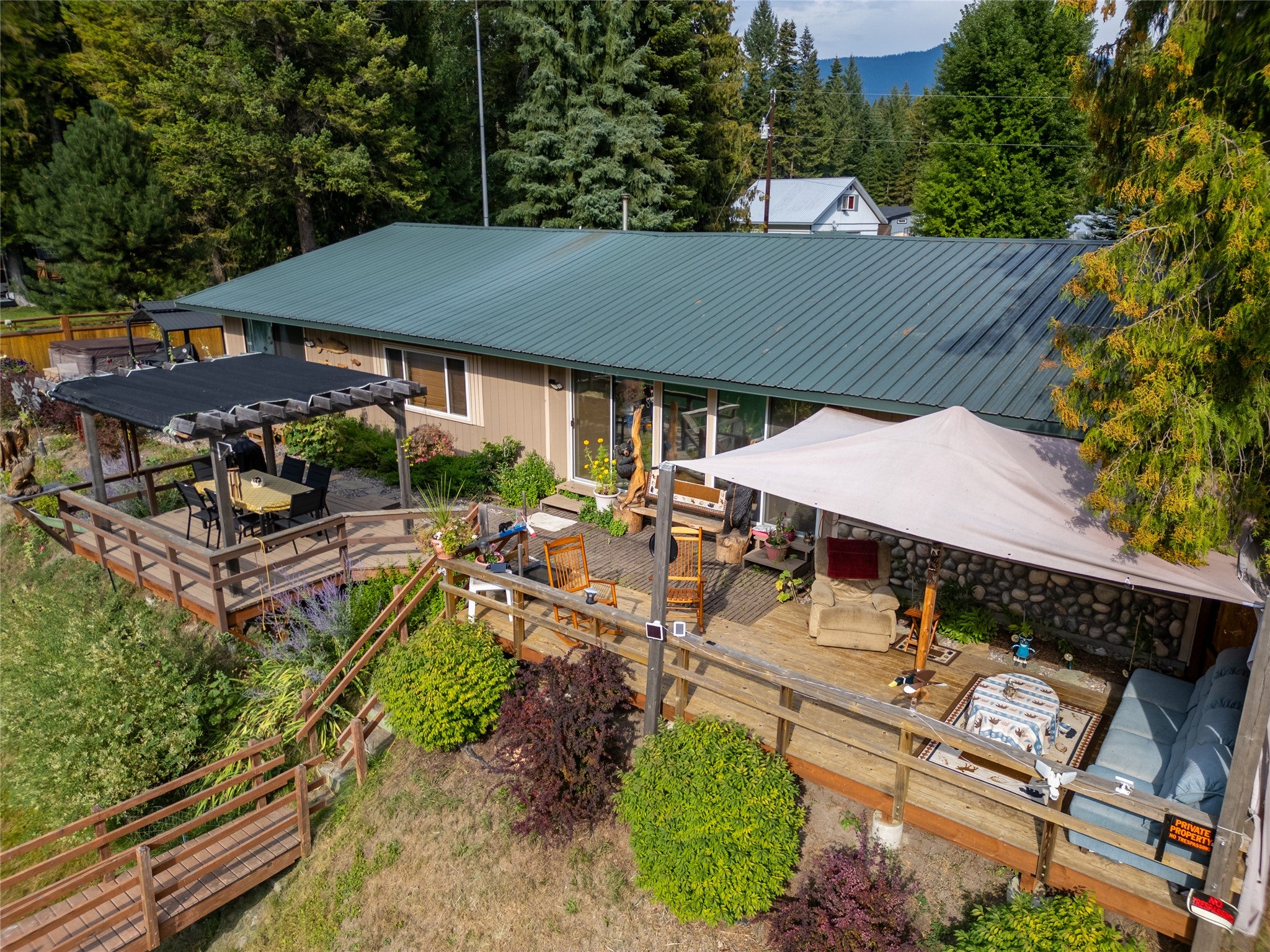 644 Waterfront Road Troy, MT 59935 - Photo 14 of 66 Back of property featuring a wooden deck, a metal roof, a pergola, outdoor dining space, and a forest view