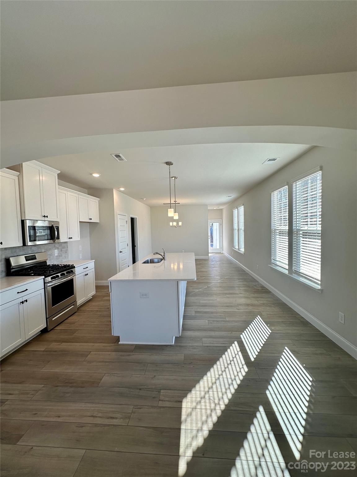 9519 Pointer Road Huntersville, NC 28078 - Photo 5 of 34 a large kitchen with kitchen island a stove a sink dishwasher and a dining table with wooden floor