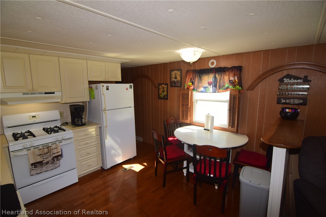 14 Henderson Road Lake Placid, FL 33852 - Photo 17 of 28 a kitchen with stainless steel appliances granite countertop a refrigerator a sink dishwasher a stove a dining table and chairs with wooden floor