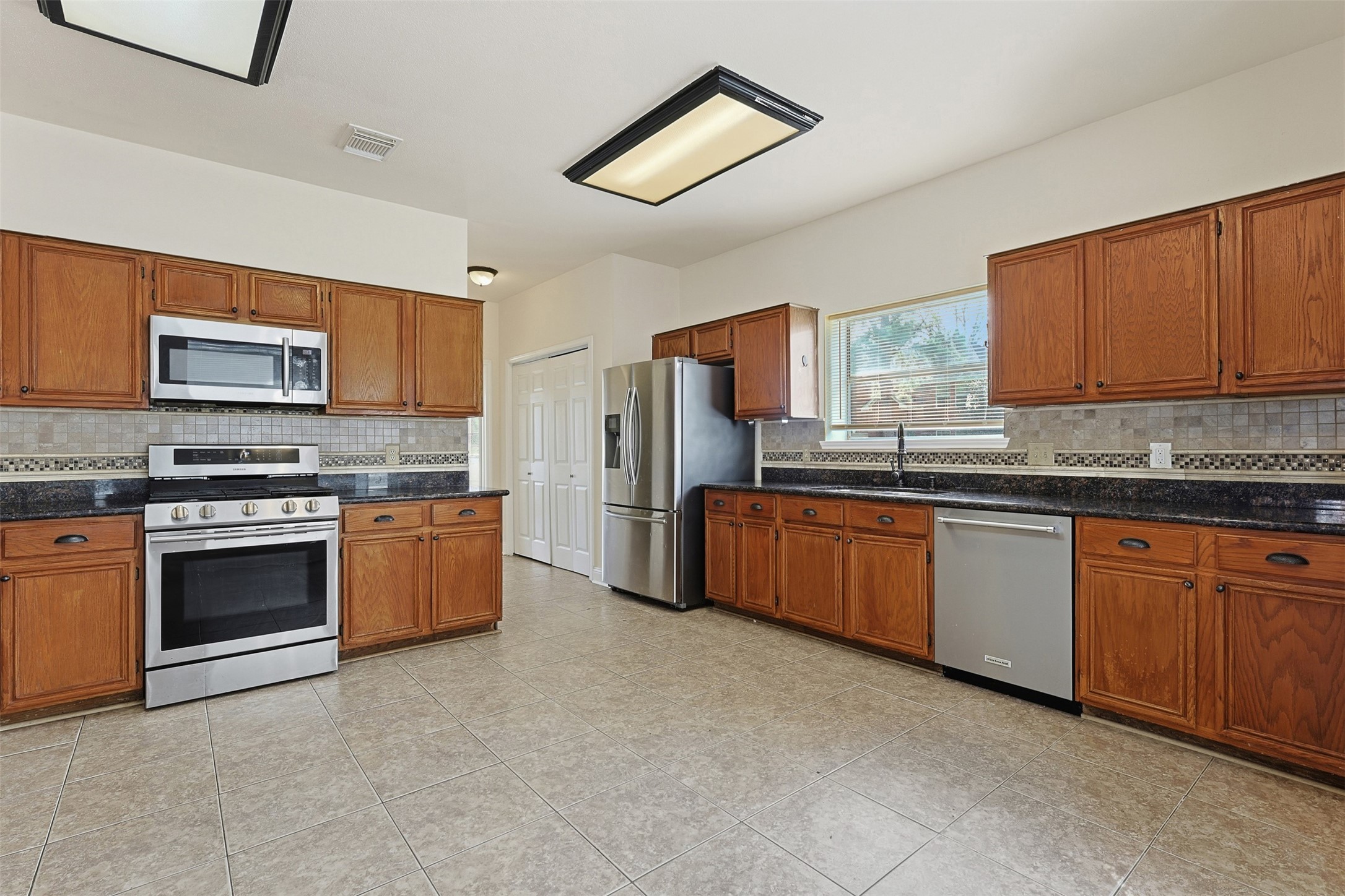 9414 Calwood Circle Spring, TX 77379 - Photo 5 of 17 a kitchen with granite countertop a stove top oven cabinets and stainless steel appliances