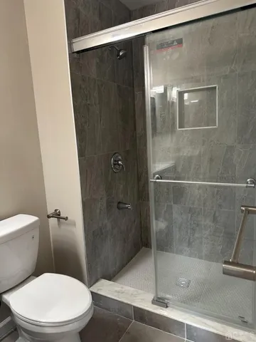 a white toilet sitting next to a shower