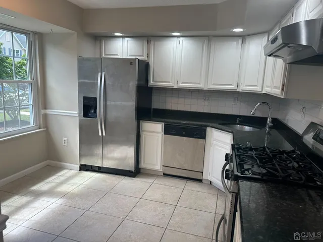 a kitchen with stainless steel appliances granite countertop a refrigerator and a stove top oven