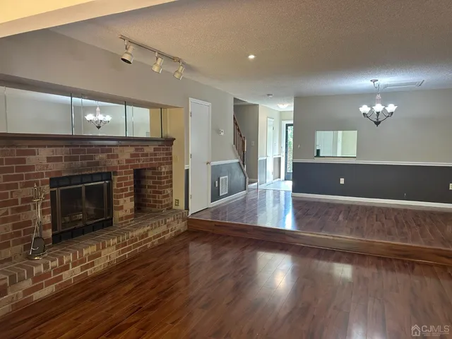 a view of empty room with wooden floor and fireplace