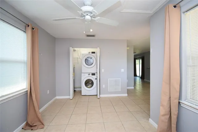an empty room with a chandelier fan and windows
