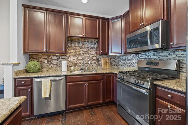 a kitchen with stainless steel appliances granite countertop a stove a sink and a microwave