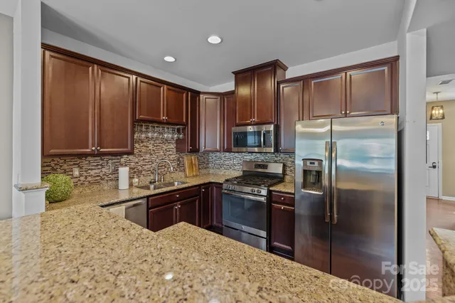 a kitchen with stainless steel appliances kitchen island granite countertop a refrigerator sink and stove