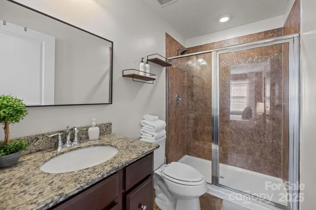 a bathroom with a granite countertop sink toilet and shower