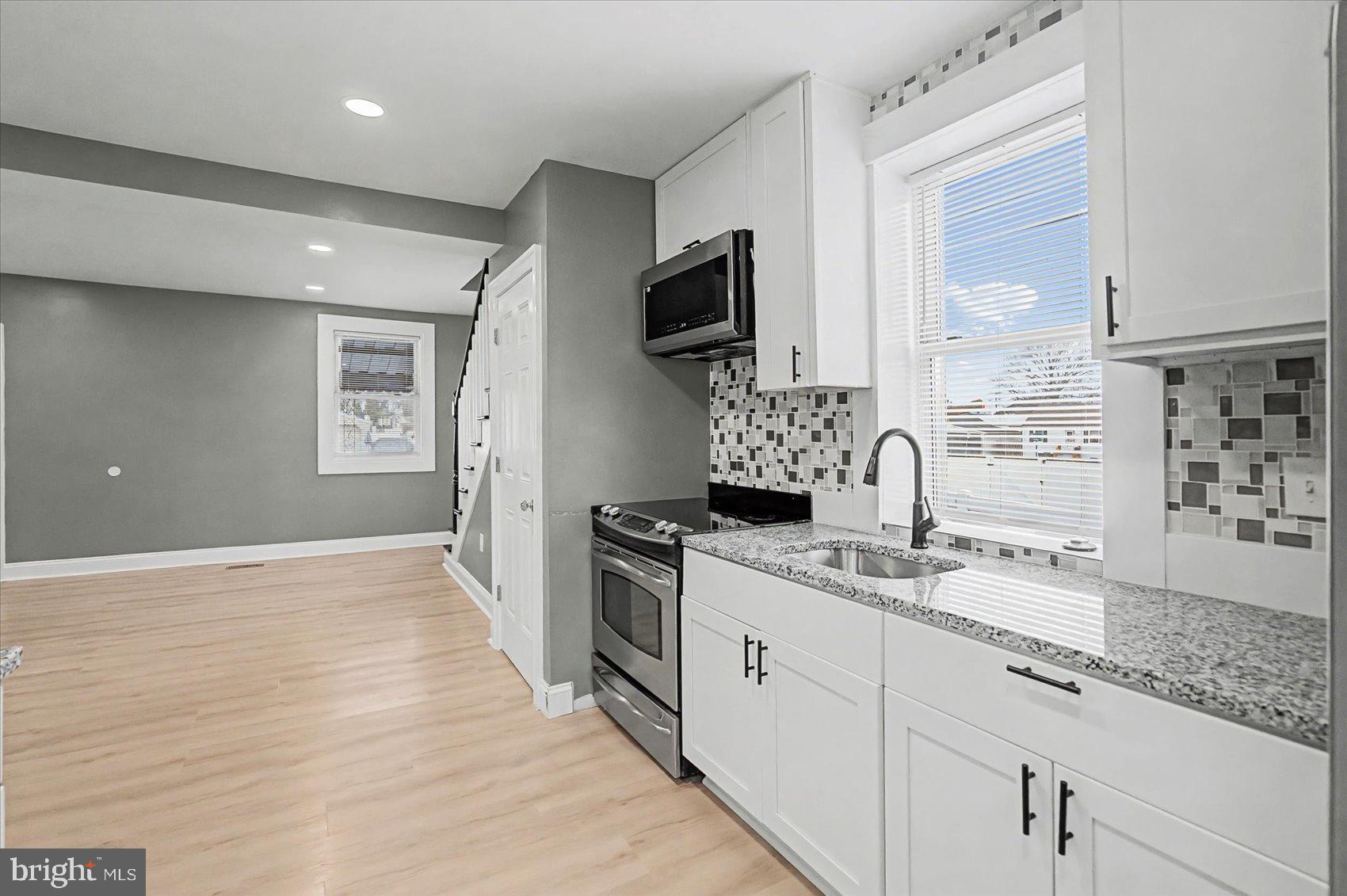 200 Pinewood Road Dundalk, MD 21222 - Photo 7 of 39 a hall with kitchen island granite countertop a sink stainless steel appliances and cabinets