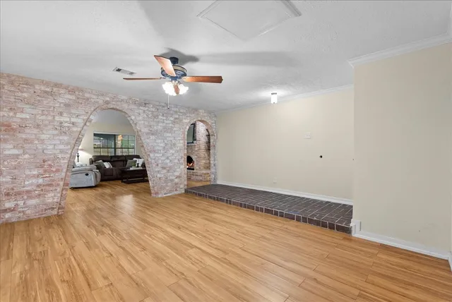 an empty room with wooden floor fan and windows