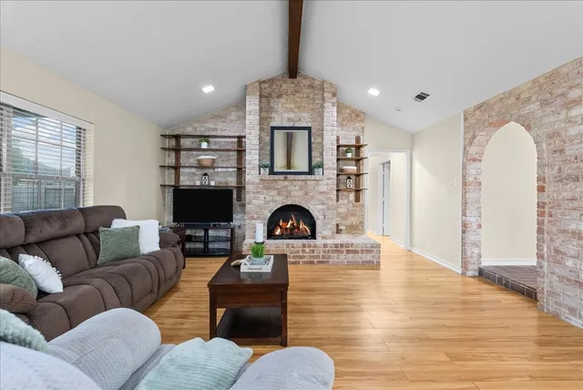 a living room with furniture and kitchen view with wooden floor