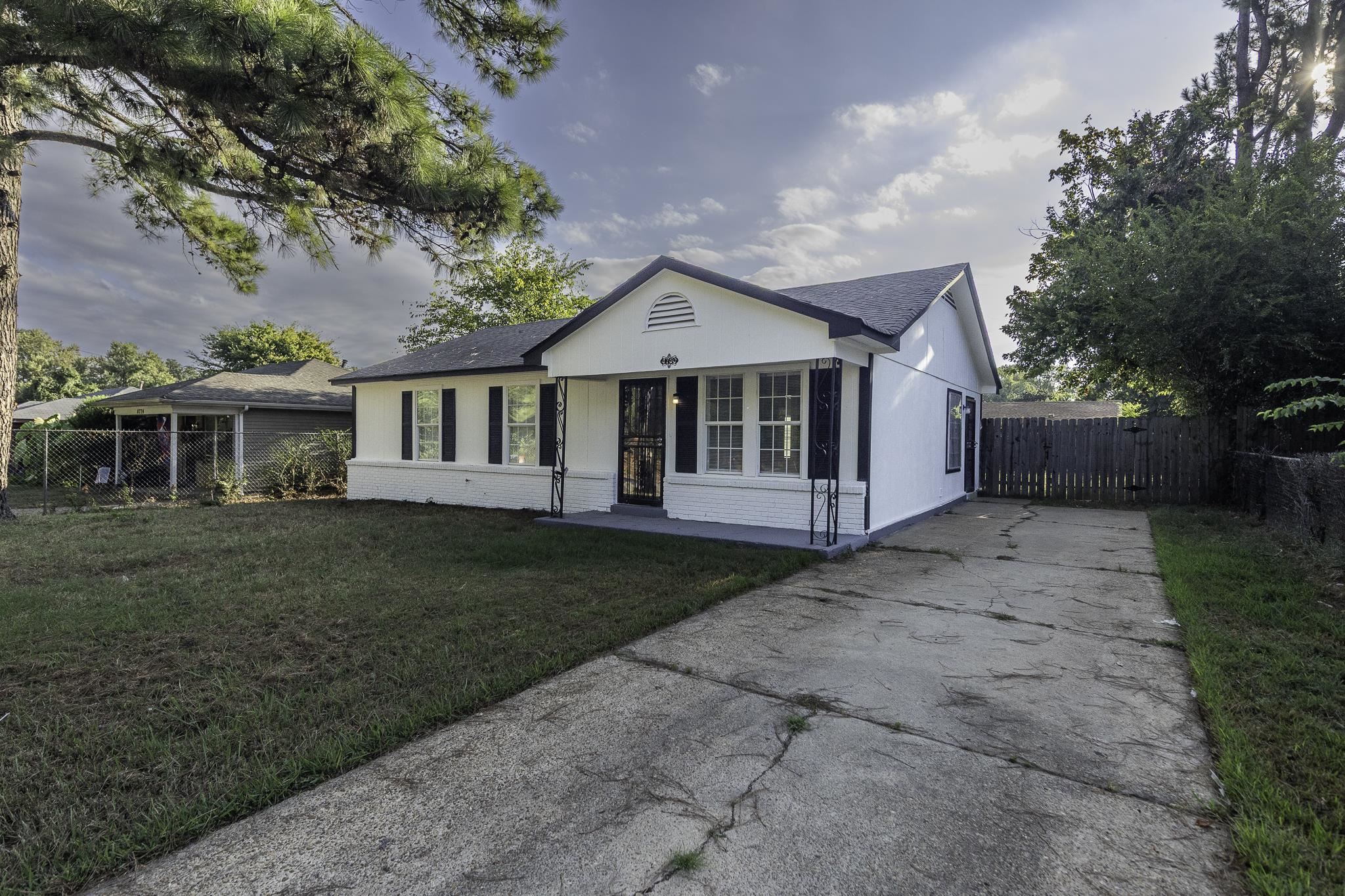 4780 Hillbrook Road Memphis, TN 38109 - Photo 6 of 25 White exterior with black shutters, covered entry with decorative metal railings, and a fenced backyard