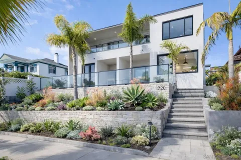a front view of a house with a yard and potted plants