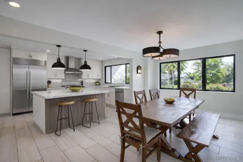 a kitchen with a dining table chairs and refrigerator
