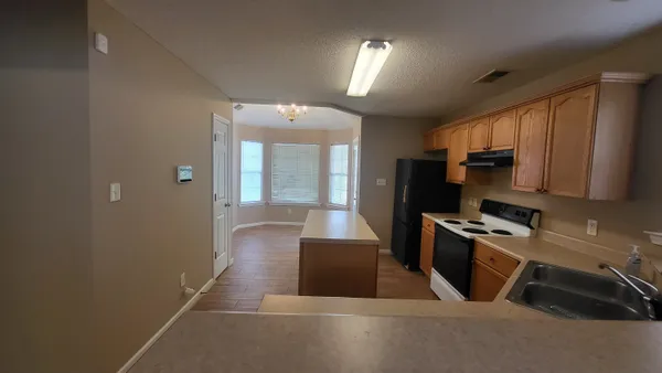 a kitchen with granite countertop a refrigerator and a stove top oven