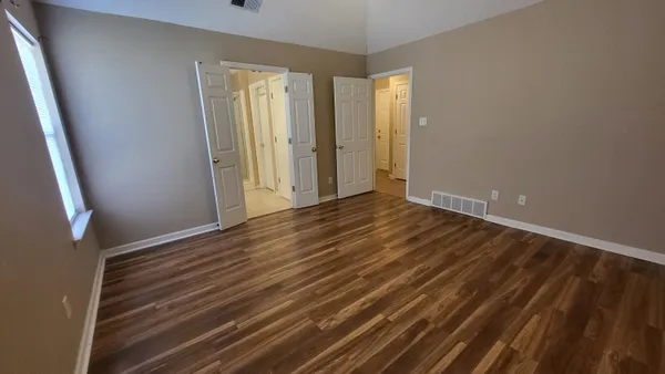 a view of an empty room with wooden floor and a window