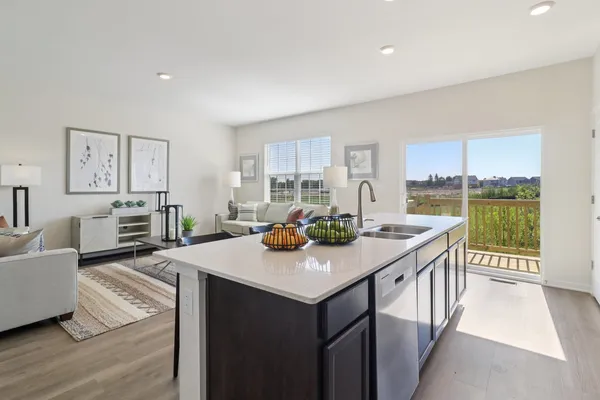 a view of kitchen island a sink and living room with a large window