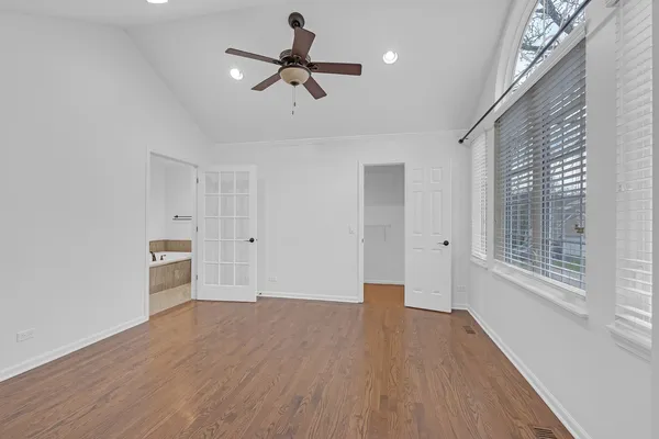 a view of empty room with wooden floor and fan