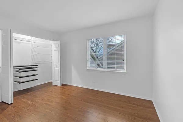 an empty room with wooden floor closet and windows