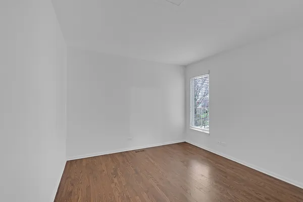 a view of an empty room with wooden floor and window