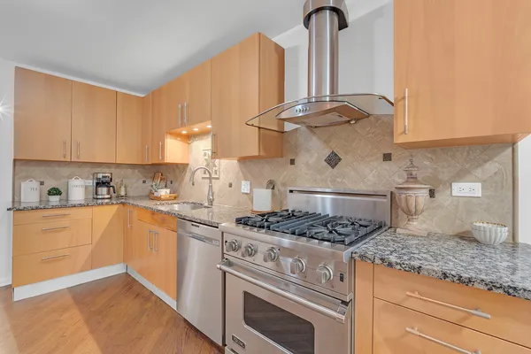 a kitchen with stainless steel appliances granite countertop a stove a sink and white cabinets