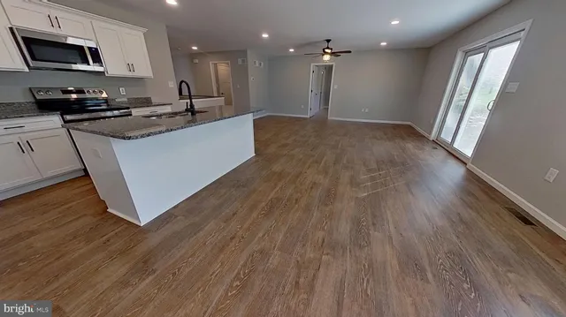 a large kitchen with granite countertop a large counter top a sink appliances and cabinets