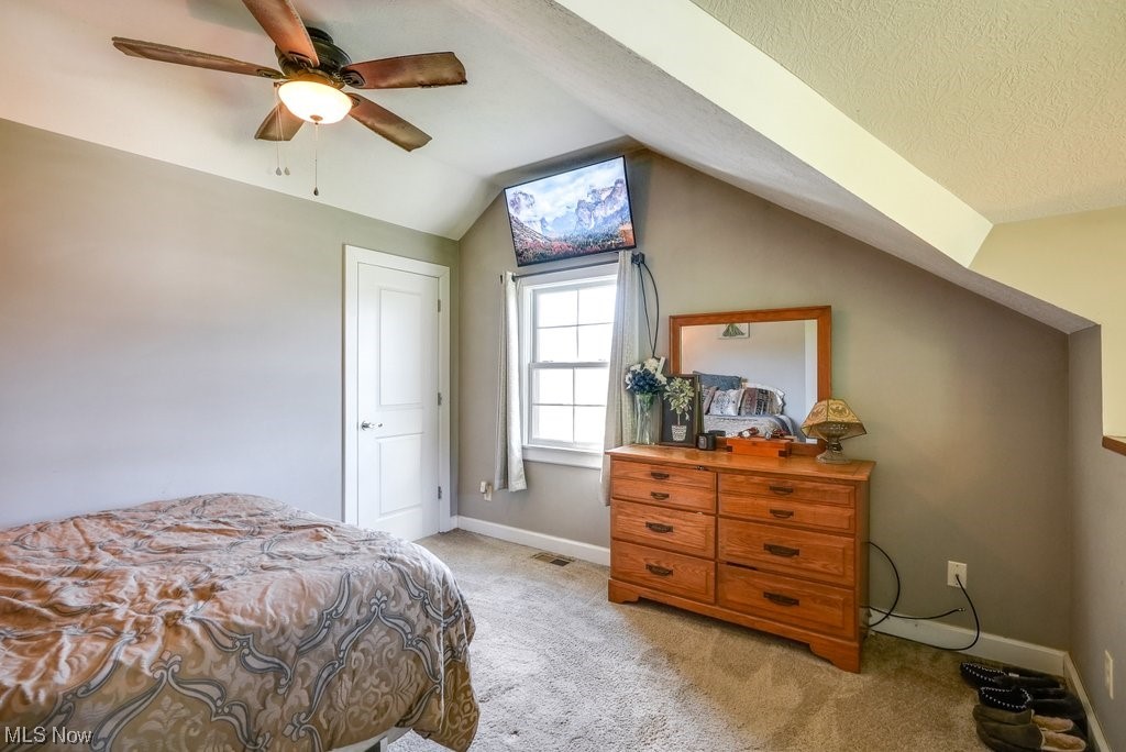 3417 Lake Rockwell Road Ravenna, OH 44266 - Photo 22 of 35 Carpeted bedroom with vaulted ceiling, ceiling fan, and a textured ceiling