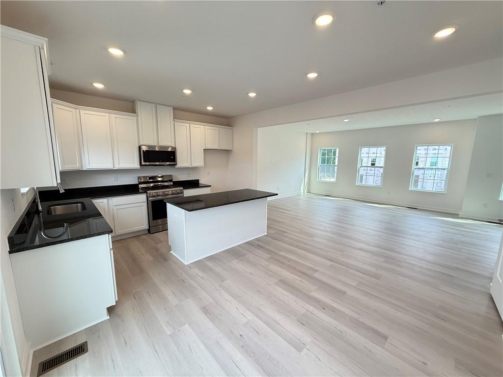 177 Lockheed Drive Coraopolis, PA 15108 - Photo 9 of 18 a kitchen with stainless steel appliances a stove a sink a refrigerator white cabinets and wooden floor