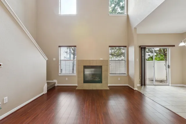 an empty room with wooden floor windows and fireplace