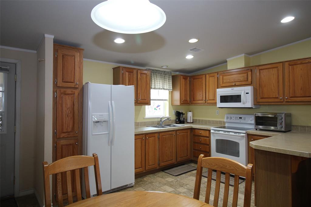 601 Carothers Avenue Rochester, TX 79544 - Photo 11 of 37 a kitchen with stainless steel appliances granite countertop a refrigerator a sink dishwasher a stove and white cabinets with wooden floor