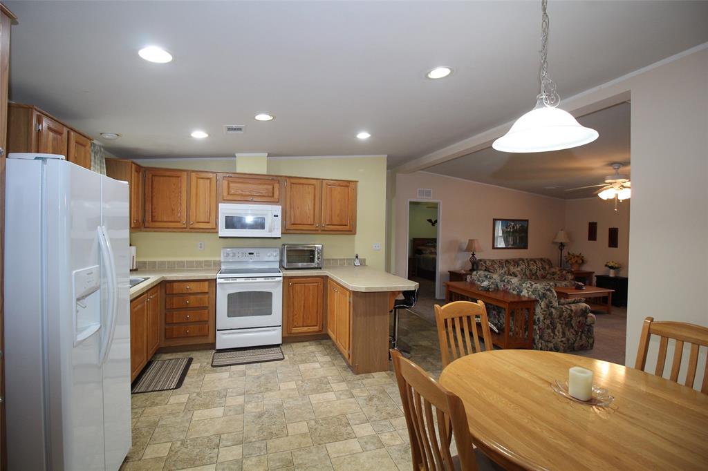 601 Carothers Avenue Rochester, TX 79544 - Photo 13 of 37 a kitchen with stainless steel appliances kitchen island granite countertop a refrigerator a stove a sink a dining table and chairs with wooden floor