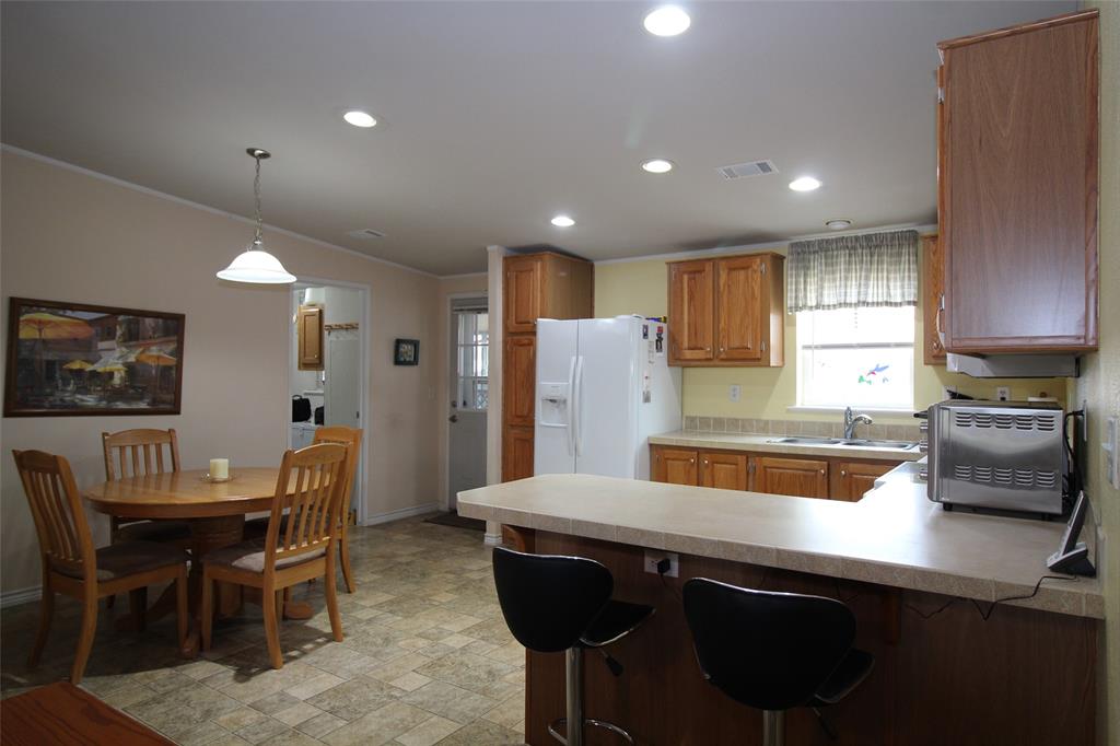 601 Carothers Avenue Rochester, TX 79544 - Photo 16 of 37 a kitchen with a table chairs sink and refrigerator