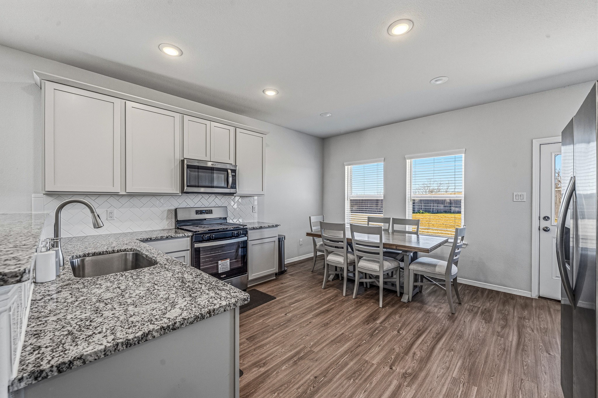 5903 Dawning Sun Road Katy, TX 77493 - Photo 12 of 37 a kitchen with stainless steel appliances granite countertop wooden floor a dining table and chairs