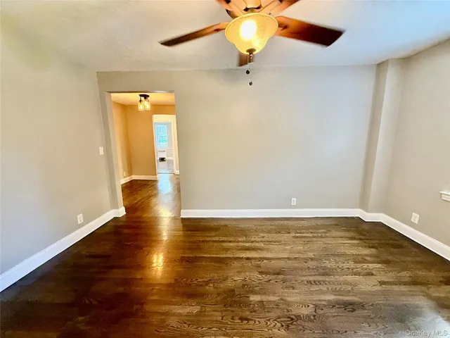 an empty room with wooden floor fan and window
